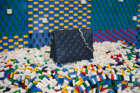 Louis Vuitton and lego collaboration. Bag at luxury brand shop window with creative colorful background. 