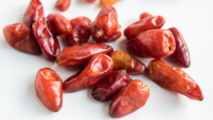 Close up of dried up pequin peppers on white background.