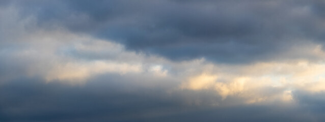 Fototapeta premium Dark clouds in the sky are slightly illuminated by the evening sun