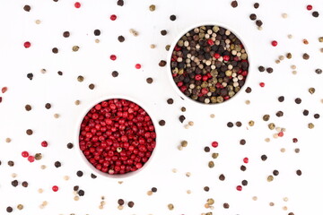 Red and black pepper peas in a white glass round plate on a white concrete, stone or slate background. view from above. close-up photo