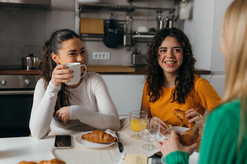Female friends drink coffee and eat croissants together