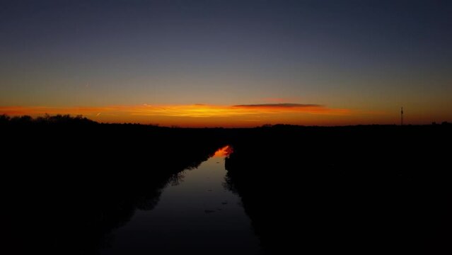 Orange sunset over the river. The river in the setting sun. Evening on the river. Drone video. Beautiful evening landscape in nature. Night fishing. The horizon is on fire.