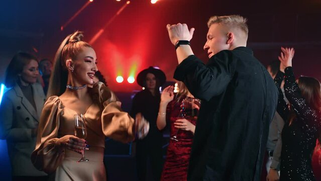 Excited smiling couple pair flirting dancing together on dance floor cocktail neon discotheque