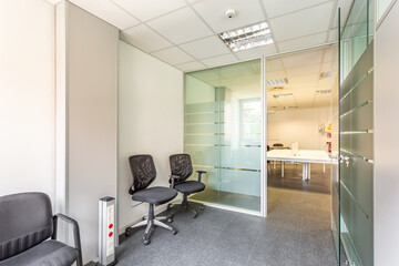 Abandoned building of an insolvent owner with an interior in a simple office style. Offices, left and right, with glass partitions and a small, sun-drenched corridor with two chairs.