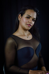 Obraz na płótnie Canvas Portrait of a serene and positive young Brazilian woman, against a dark background