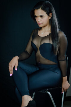 Portrait of a beautiful young Brazilian woman sitting on a stool and wearing a skintight body suit