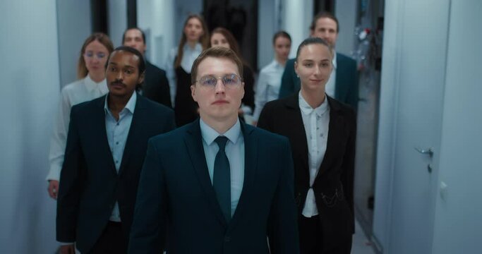 team of multiethnic businesspeople walking in office center corridor, frontal view, 4K, Prores