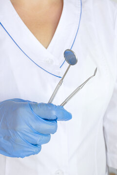 Cropped view of dentist in latex glove holding Dentist Professional tool near dental set blurred on of doctors coat uniform background.