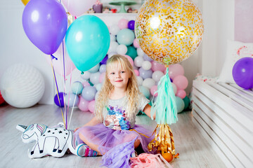 A joyful child in a pretty dress posing with sparkling balloons at a birthday party.