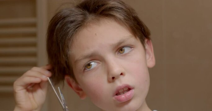 Close-up of a face He pulls his hair with his hands and wants to cut the curl, stops. Reflection of the transitional age of a boy trying a new style.