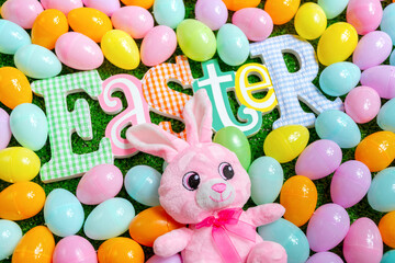 Easter word an plush bunny on a faux grass surrounded by plastic eggs
