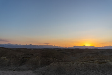 Fototapeta na wymiar Sunset in the Hurghada desert, with the desert mountains on the horizon