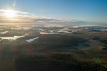 Foggy morning on a beautiful lake surrounded by forests and fields. A small village located near a lake in fog and morning sun.