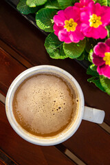 cup of coffee and spring flowers primrose multicolored on the table copy space food background rustic top view