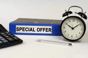 On a white surface, an alarm clock calculator and a folder with the inscription - Special Offer