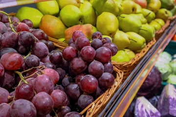 ripe juicy fruits on the counter in the store. ripe red grapes and juicy yellow pears are sold at the farmers market