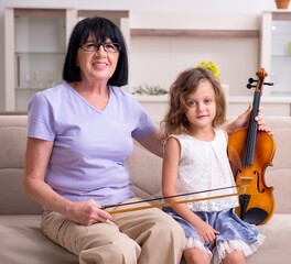 Old lady teaching little girl to play violin