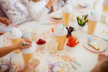 festive table with disposable tableware with unicorn motif and vegetables, healthy food. Birthday in unicorn style, decorating ideas. Happy childhood concept