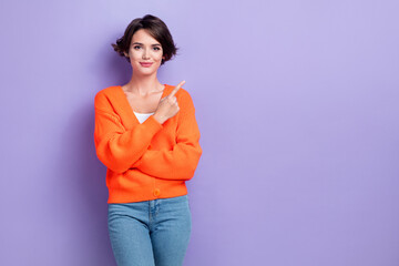 Photo of sweet charming lady dressed orange cardigan smiling showing finger empty space isolated purple color background