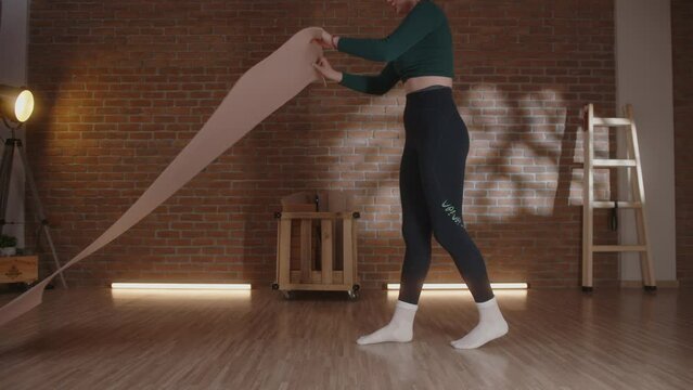 Young woman putting yoga mat on floor and stretching body