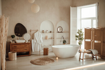 Obraz na płótnie Canvas Soft native hues organic shapes look of bathroom with big window oval bathtub in neutrals tones. Green palm plants candles bubblebath leasure and relaxation skin selfcare wellness luxury living