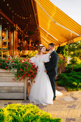 the bride and groom embrace on the terrace in the park near the restaurant.