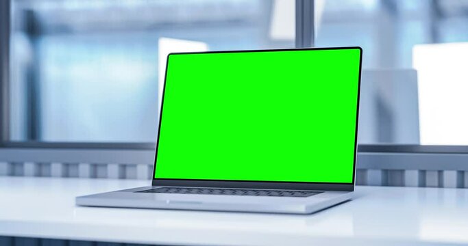 Laptop with blank green screen in industrial office or medical interior. Smooth camera movement around object with bokeh background. Chroma key and tracking mask included.