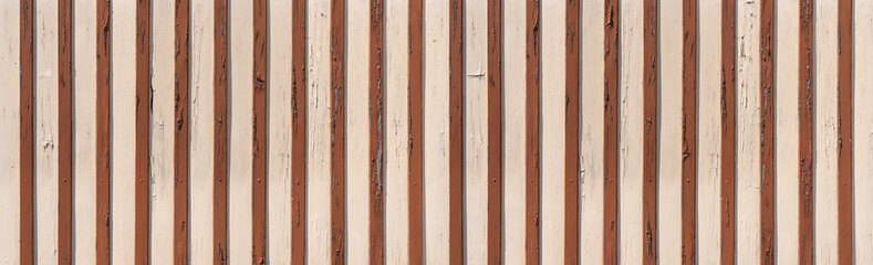 Helle, gestrichene, verwitterte alte Holzwand mit aufgesetzten braunen vertikalen Holzleisten