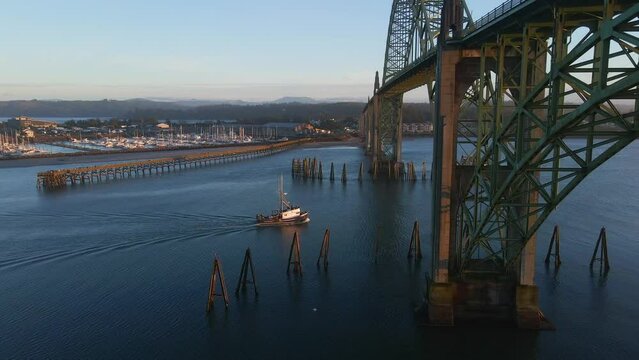 Drone Aerial Video Yaquina Bay Bridge Newport Oregon Coast Landmark Highway 101 09 Slow motion forward aerial view of a fishing boat crossing under Yaquina Bay Bridge