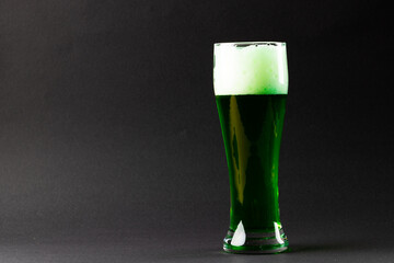 Image of glass with green beer and copy space on grey background