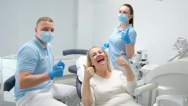 dental office satisfied patient showing thumbs up big class liked service new technologies masked doctor and assistant are also happy with the result of work smile joy healthy teeth latest technology