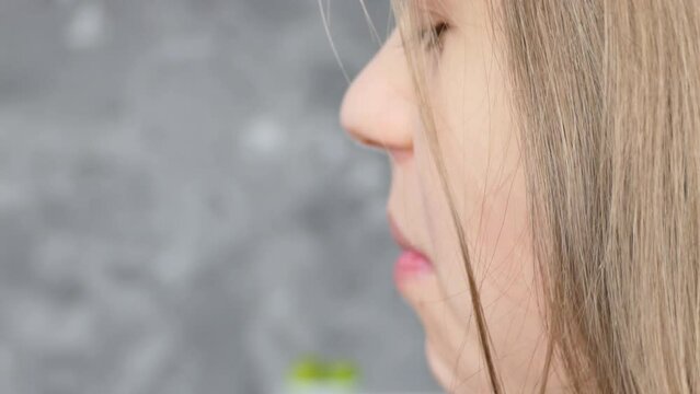 Close-up portrait: a happy beautiful young girl appetizingly bites a pink donut, licks her lips and laughs. The girl in the kitchen eats sweets cheerfully, happily. 4K