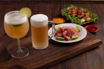 Beer mug on wooden board with portion of fried chicken and sausage