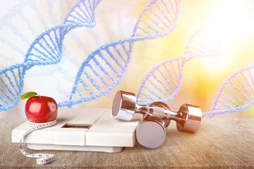 DNA structure, sport dumbbells and tape measure on desk