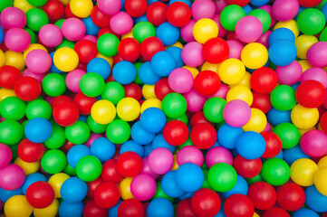 Fototapeta na wymiar Top view of many multicolored plastic balls in a ball pool at a children's indoor playground. Recreation and entertainment concept.