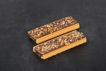 Two Crispy cookie strips with chocolate, peanuts and cereals. Dark gray  background