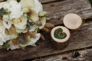 Fototapeta na wymiar A box for wedding rings made of wood with floral decor lies on a wooden surface. Wedding accessories.