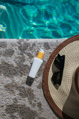 white mock up sunscreen bottle at the pool with sunglasses and summer hat