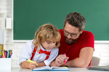 Teacher helping child student pupil from elementary school in classroom. Pupil kid student and teacher tutor in classroom at school lesson.