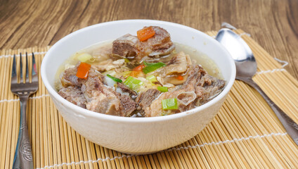 Sop Iga (Beef ribs soup) is Indonesian soup. served in white bowl. selective focus