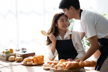 Lovely Asian couple cooking dinner together, spending time together in wooden minimal kitchen room..