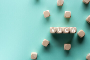 There is wood cubes with the word VUCA. It is an acronym for Volatility, Uncertainty, Complexity, Ambiguity an eye-catching image.