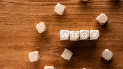 There is wood cubes with the word . It is an acronym for Wish, Outcome, Obstacle, Plan an...