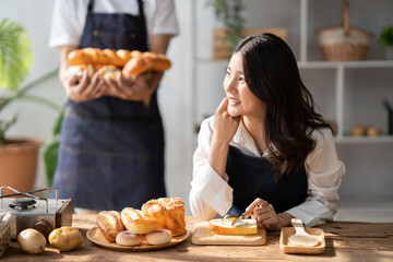 Young beautiful woman sitting the the comfortable kitchen room, waiting for her husband to serve the bake bread for her.