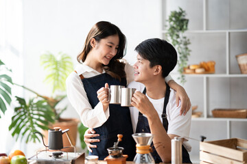 Young smiling couple in love spending a weekend morning together while making coffee at the kitchen, having breakfast together.