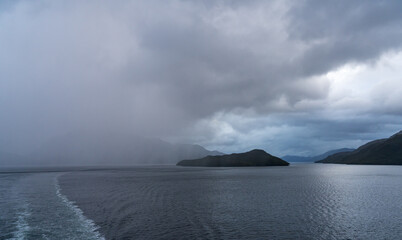 Rain over the mountains as cruise ship sails through the fjords of Chile and Patagonia