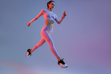 Naklejka na ściany i meble Athletic active woman jumping on studio background. Dynamic movement