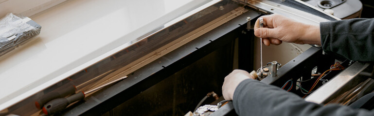 Close up of repairman with screwdriver fixing coffee machine at table indoors