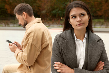 Upset arguing couple sitting on bench in park. Relationship problems