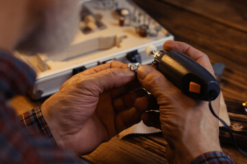 Professional jeweler working with gemstones at wooden table, closeup